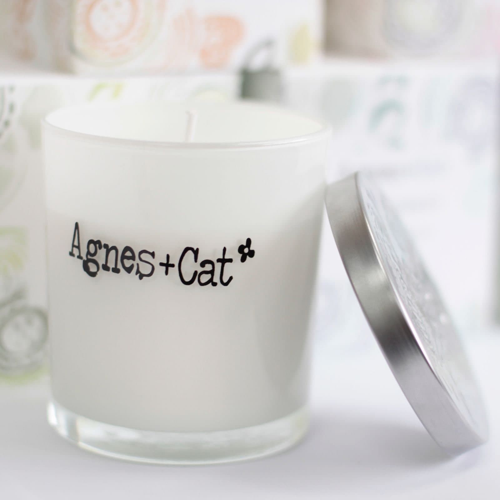 White glass Agnes + Cat votive candle with a silver lid