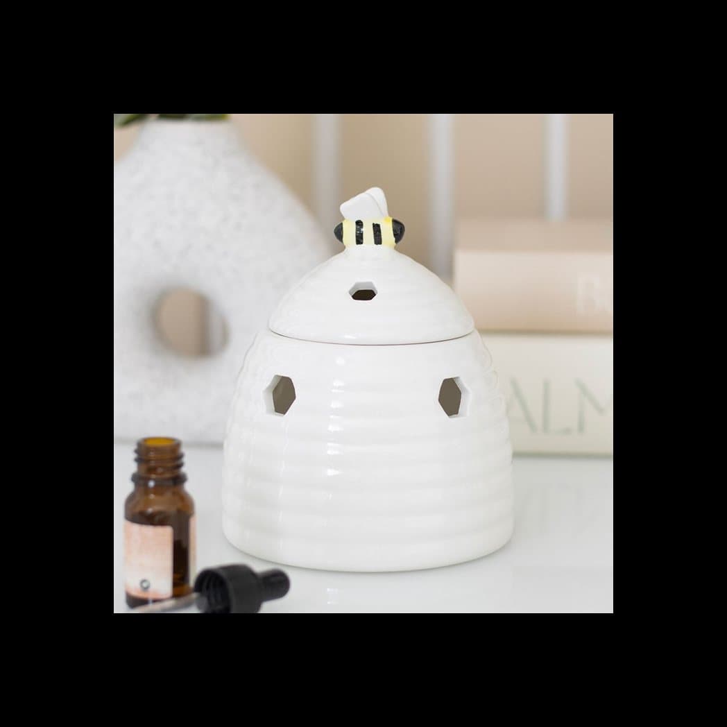 Ceramic beehive oil burner with a bee on the lid and honeycomb cutouts
