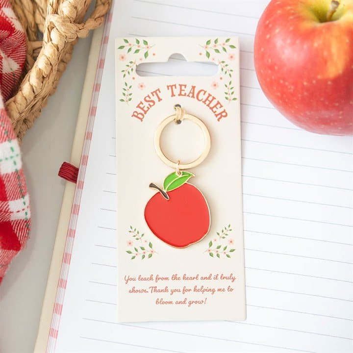 Apple-shaped enamel best teacher keyring on its cardboard back