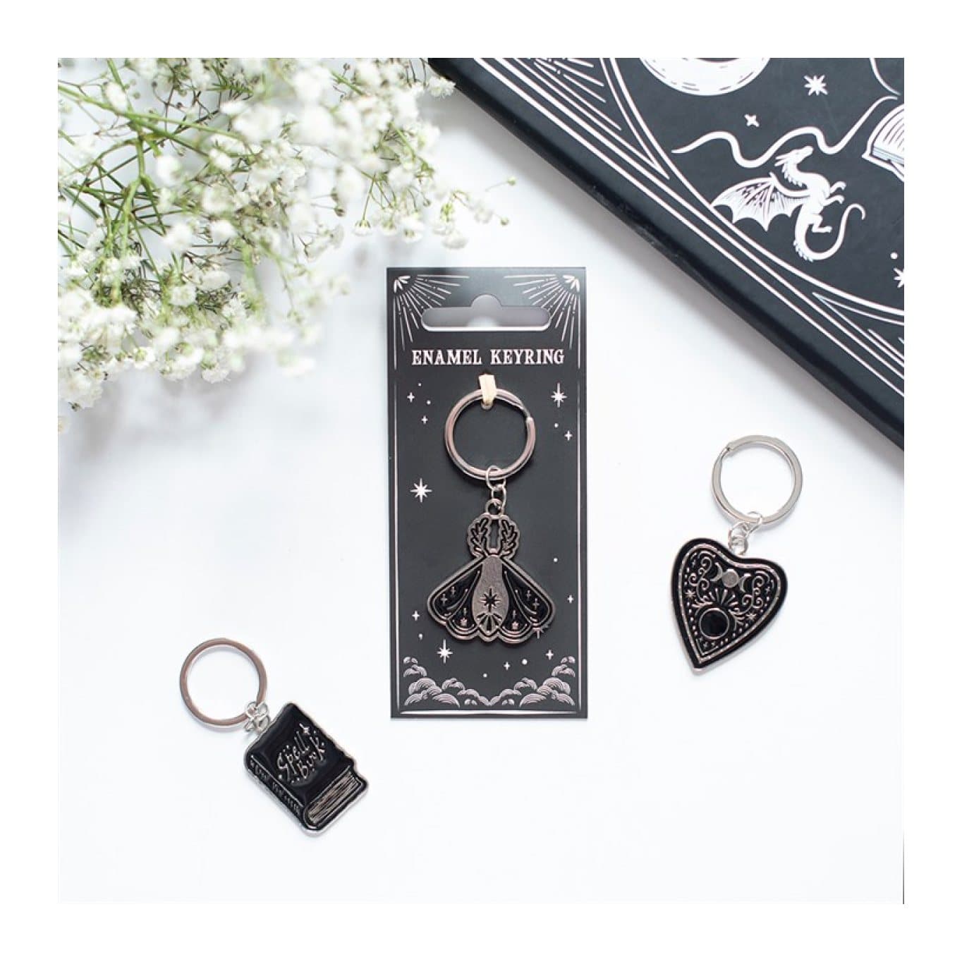 Black moth keyring with celestial details on its cardboard back
