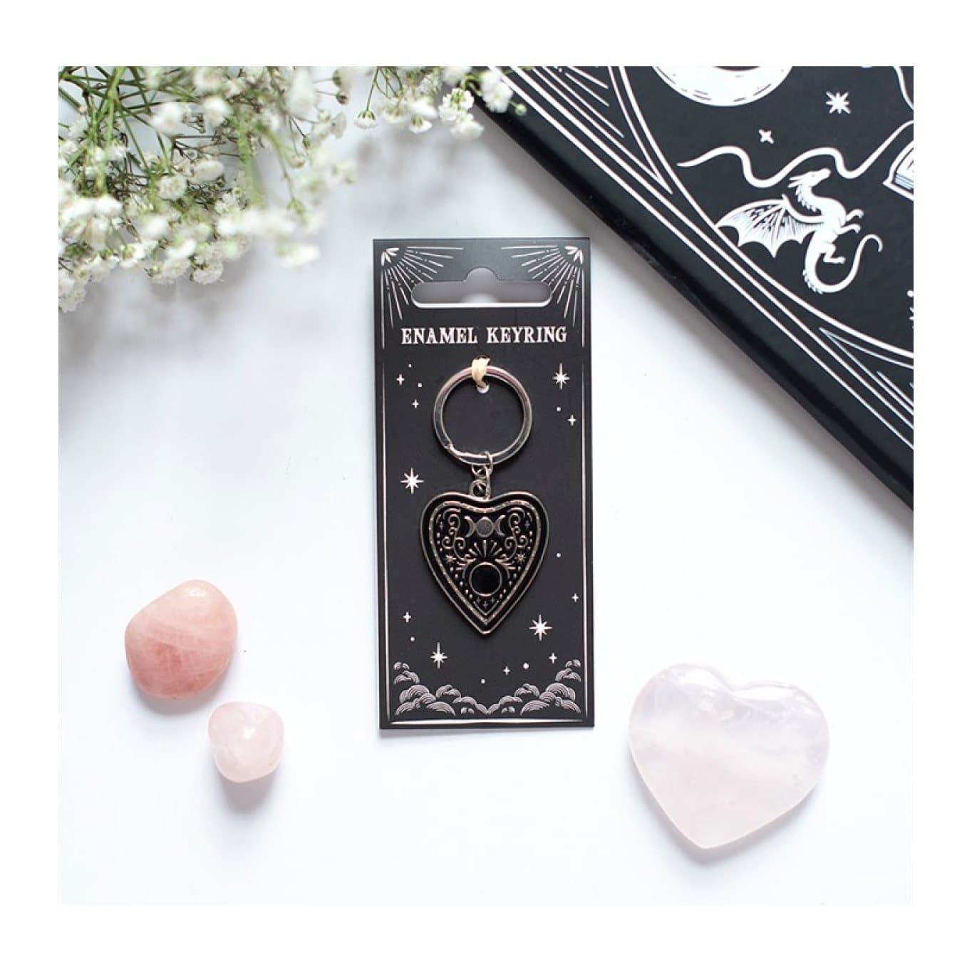 Black planchette keyring with celestial design on its cardboard back