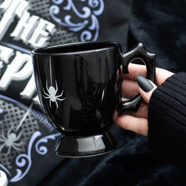 Black ceramic teacup with a thorny handle and a spider print