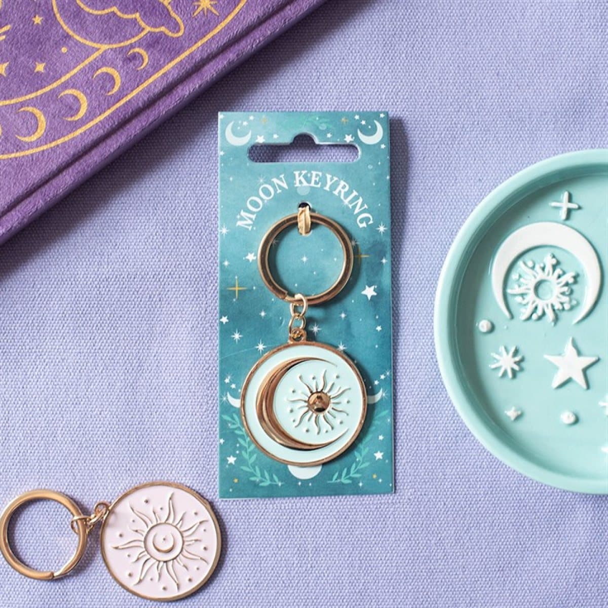 Blue moon keyring with gold-coloured accents on a decorative backing card