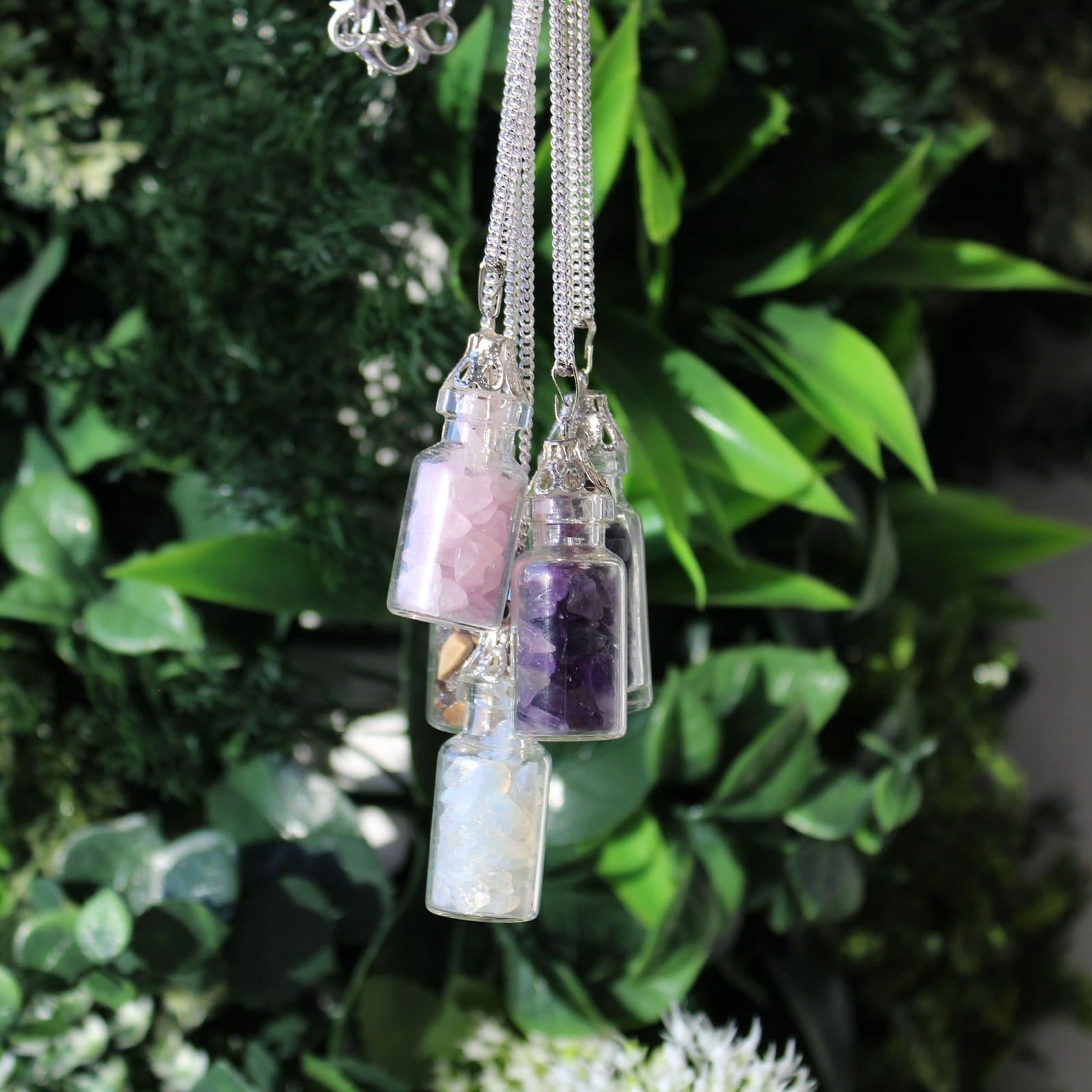 Glass bottle necklace filled with rose quartz