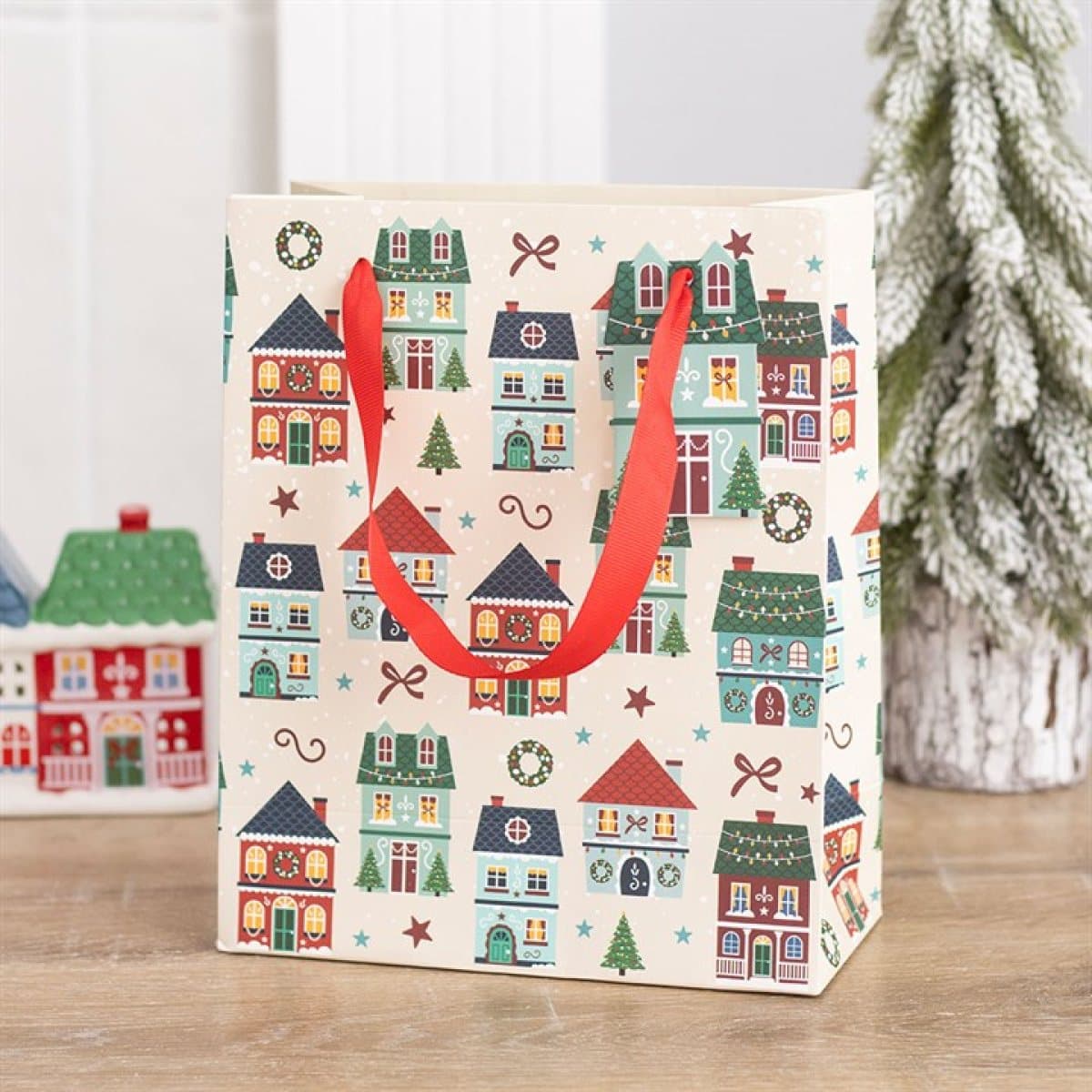 Paper Christmas gift bag printed with houses, bows and trees