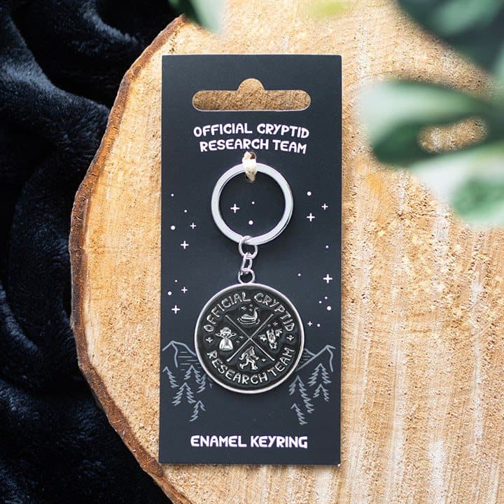 Enamel Cryptid Research Team keyring on a cardboard backing card