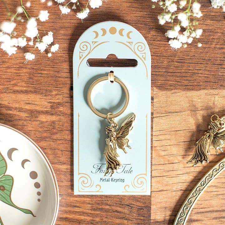 Antique gold metal keyring with a winged fairy figure on a cardboard back