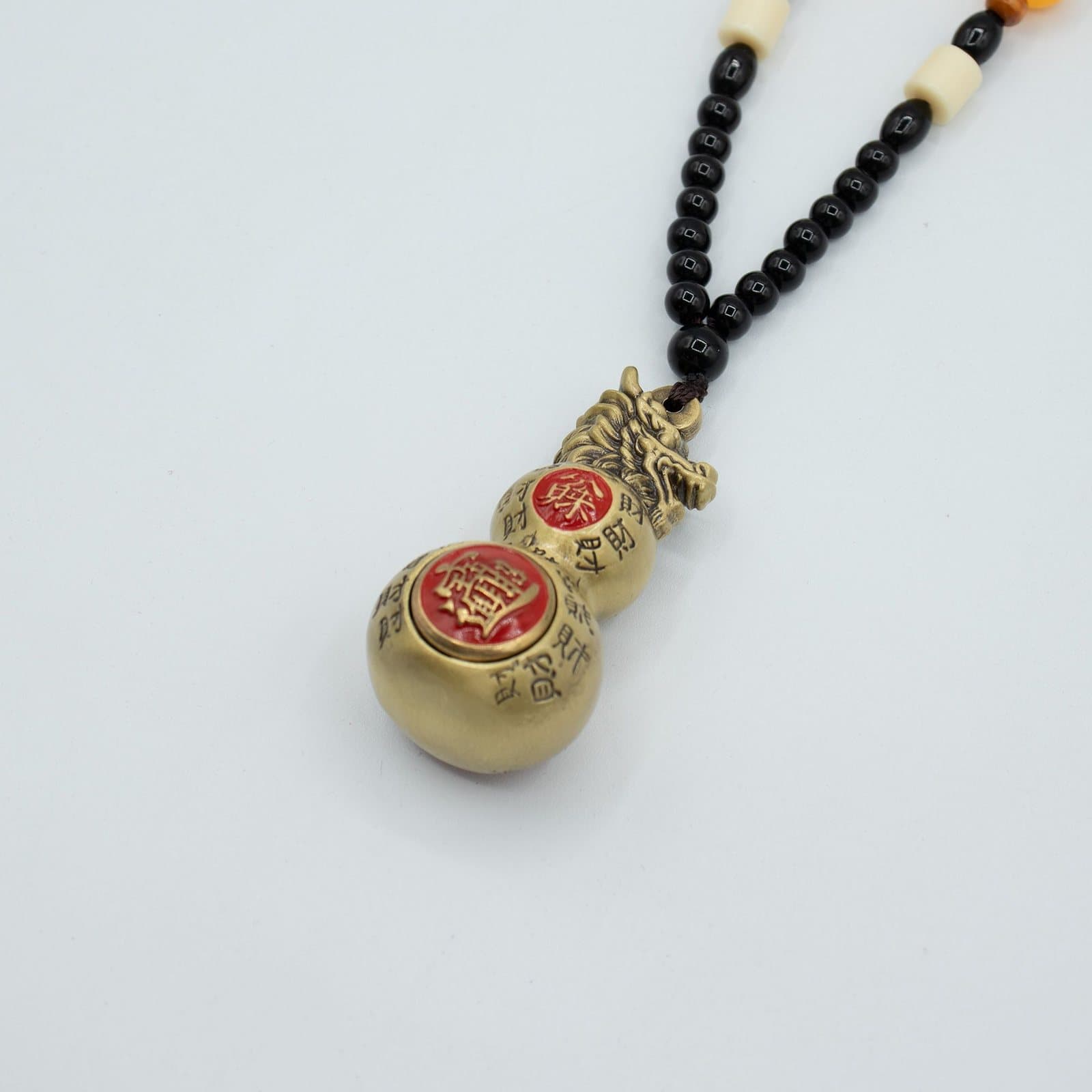 Brass double gourd hanging topped with a dragon head on a beaded cord