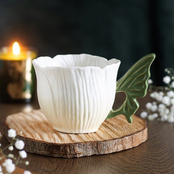 Flower-shaped ceramic teacup with a sculpted green fairy wing handle