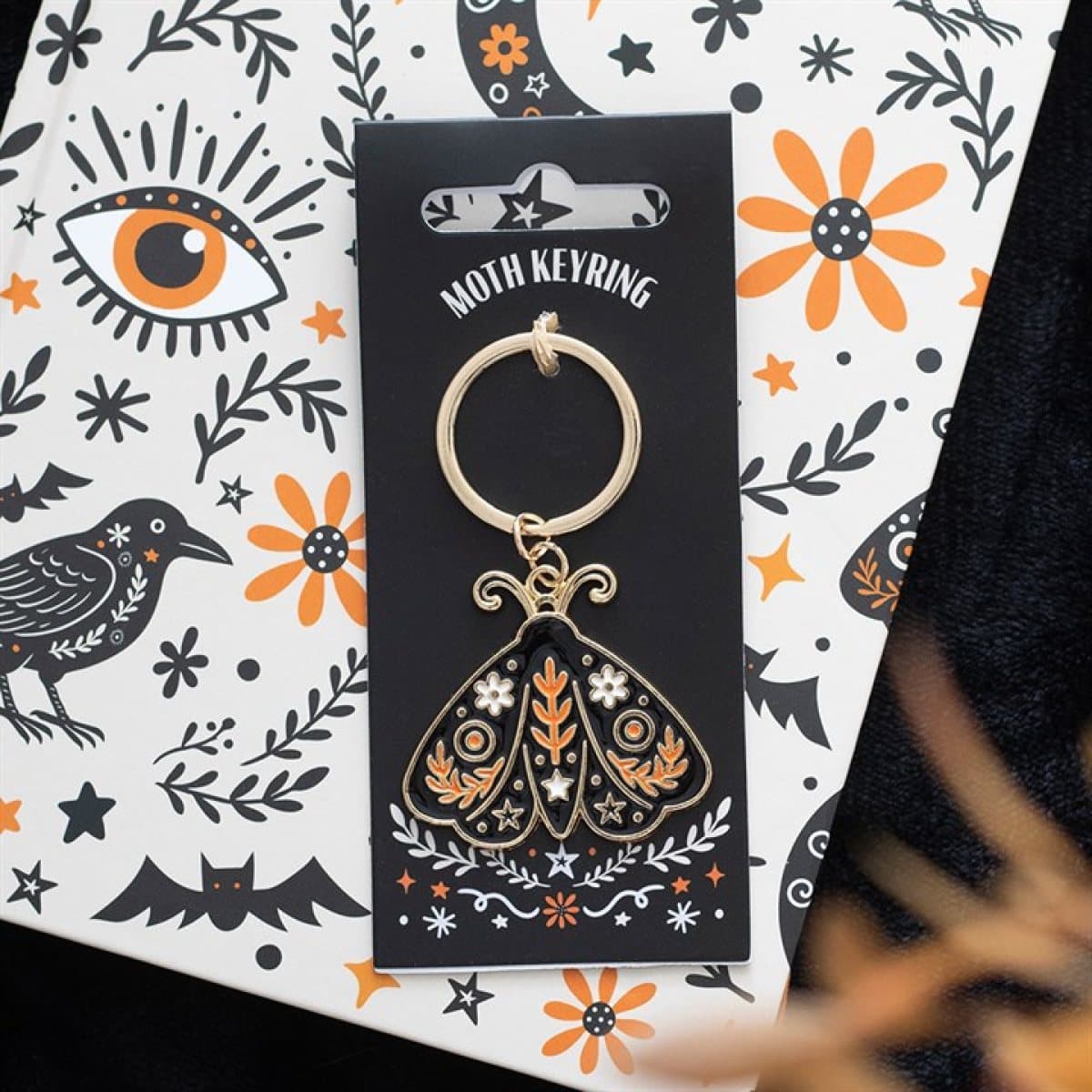 Folk moth keyring with a detailed enamel design on a cardboard back