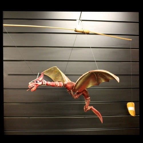 Large handmade coconut dragon mobile with spread wings hanging from a hook