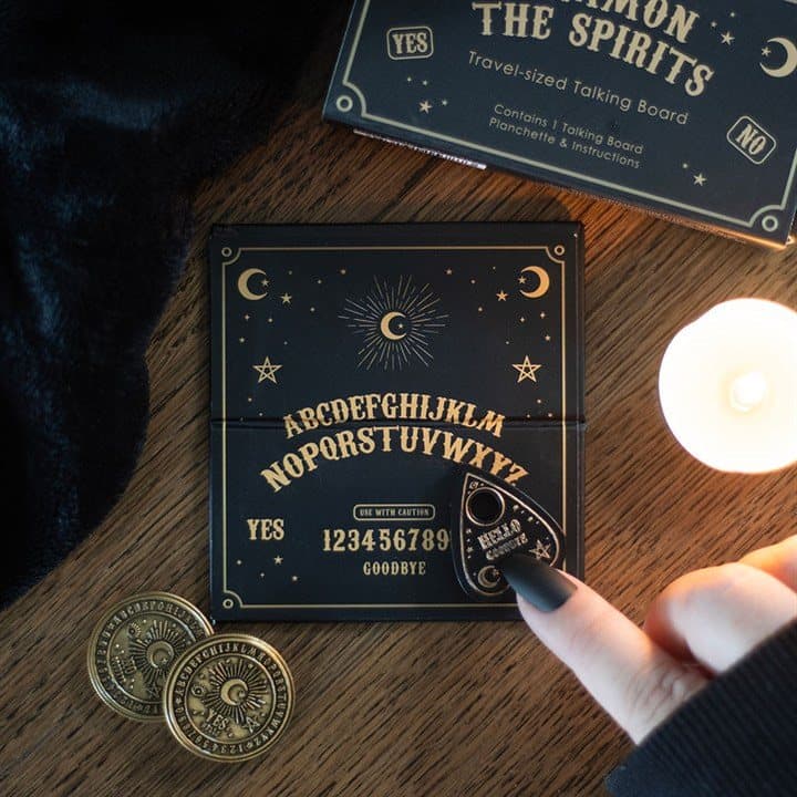 Mini travel talking board with black and gold planchette in a cardboard box