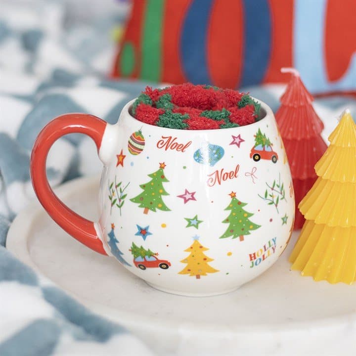 Ceramic Christmas print mug with a red handle next to a pair of stripy socks