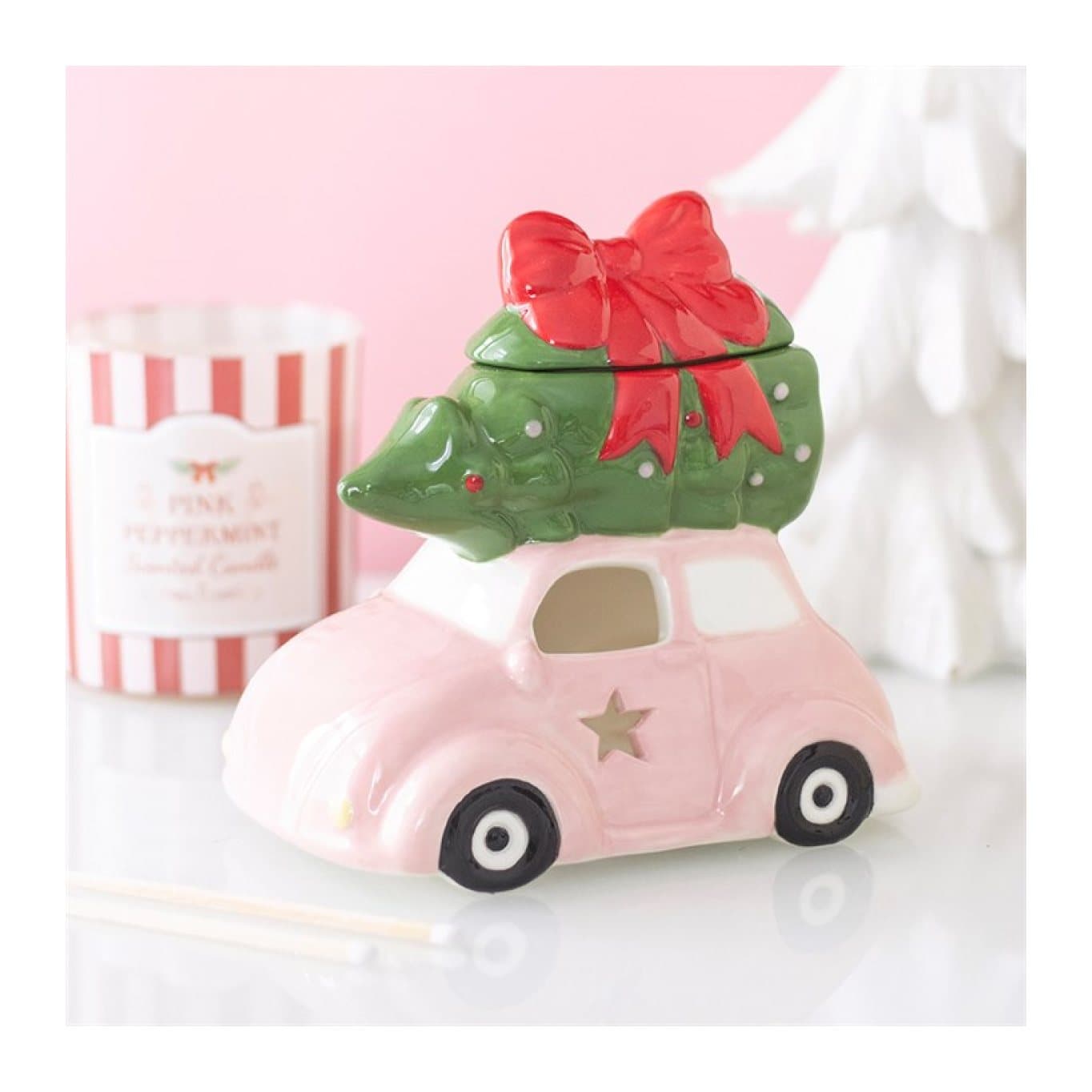 Ceramic pink car carrying a Christmas tree with a red bow