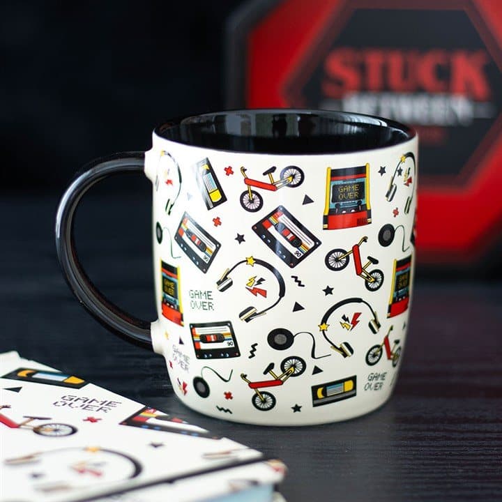 Ceramic mug covered in retro cassette tapes, bikes, headphones and gaming icons