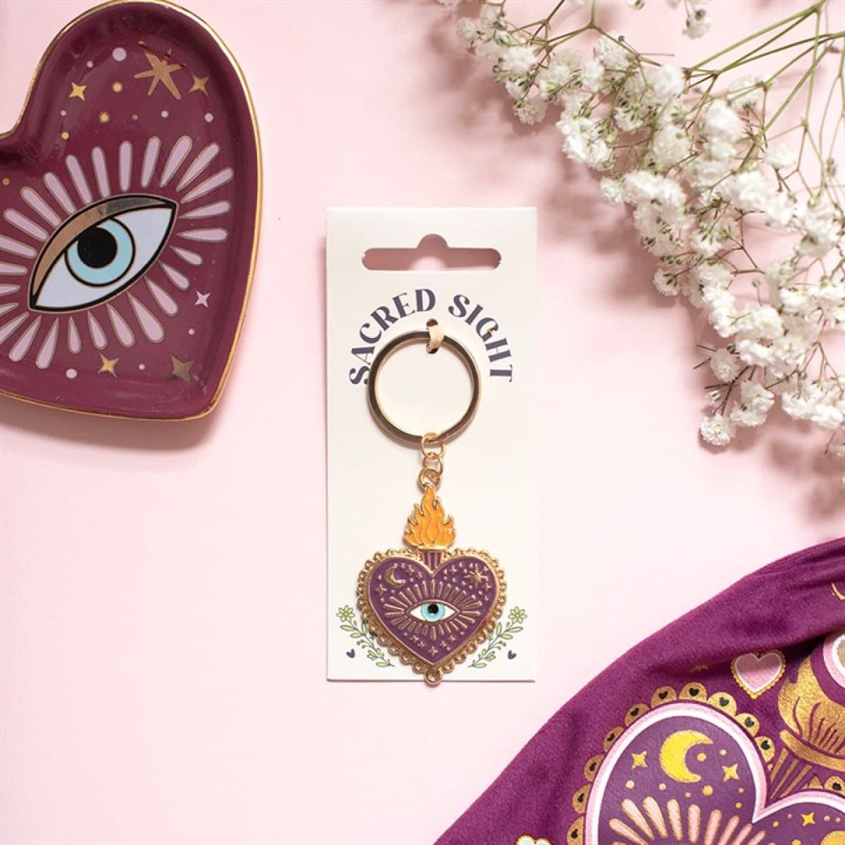 Heart-shaped all-seeing eye keyring with celestial detailing on a cardboard back