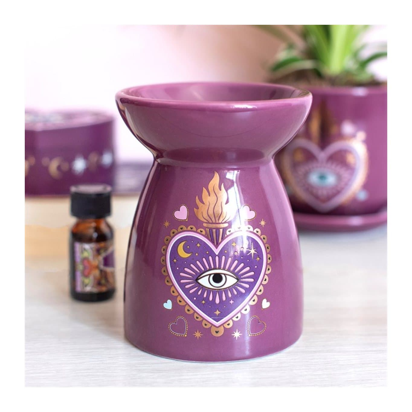 Purple ceramic oil burner with a sacred heart and all-seeing eye design