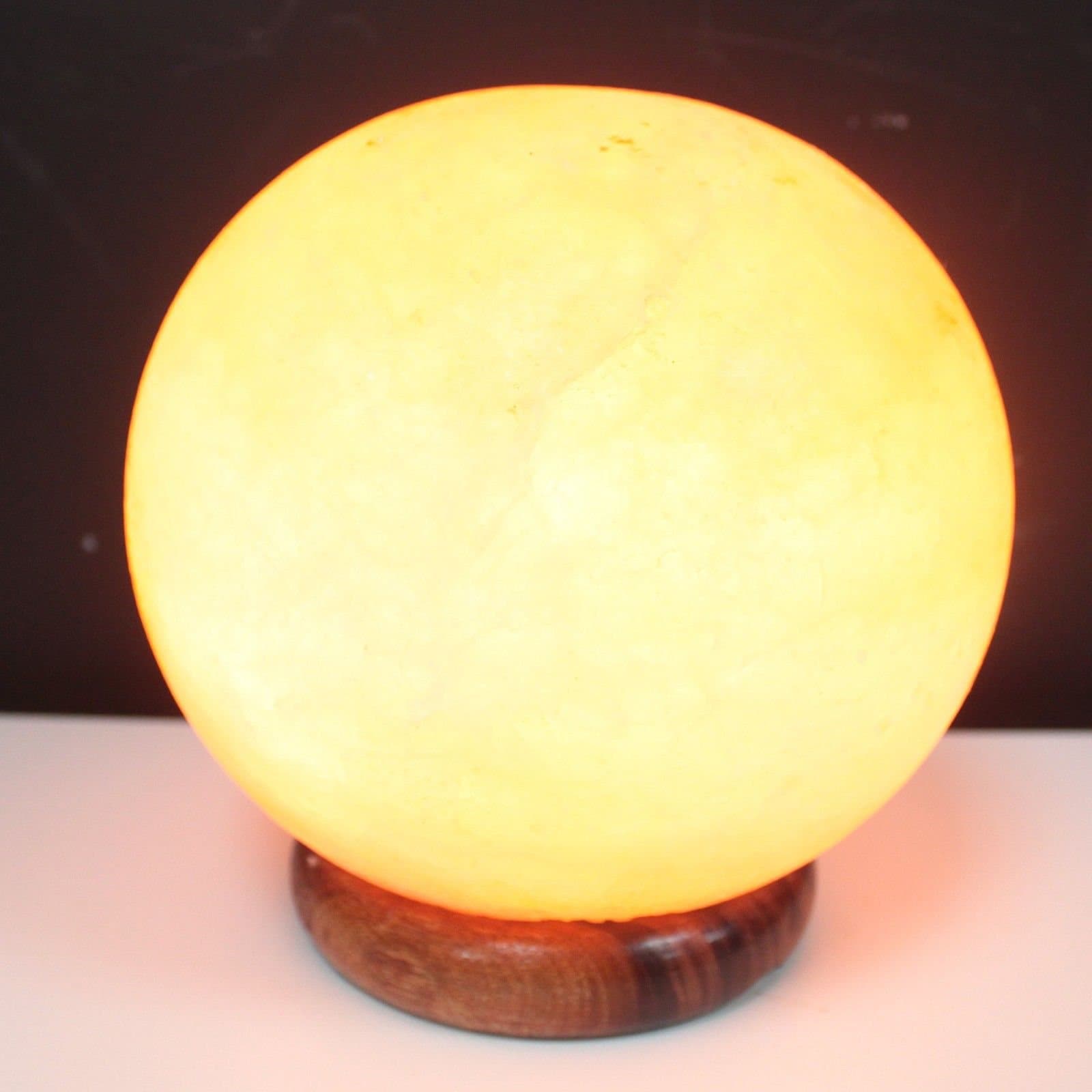 Polished salt lamp ball on a wooden base