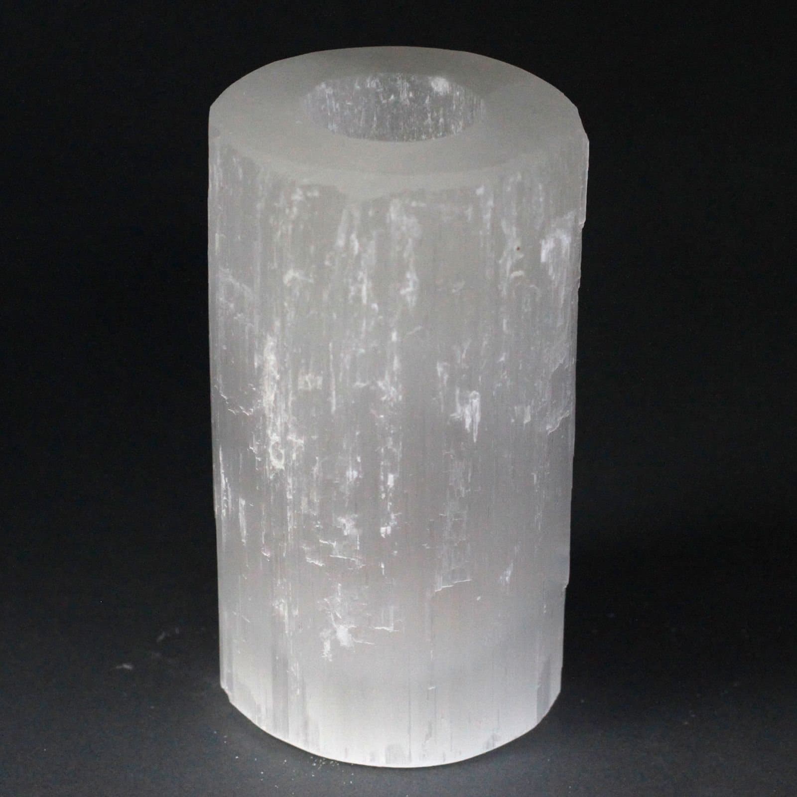 Translucent selenite cylinder candle holder with a polished top and rough edges