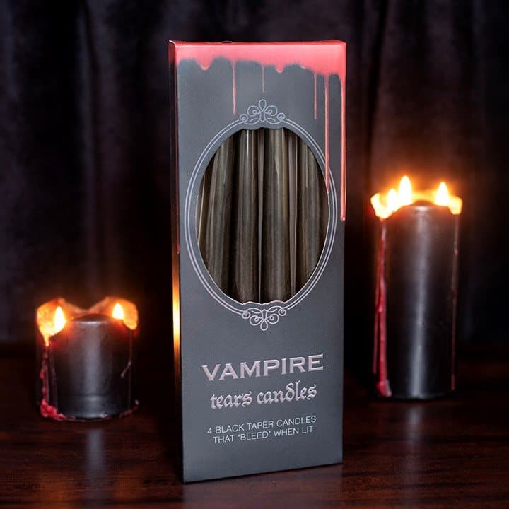 Four black taper candles dripping red wax