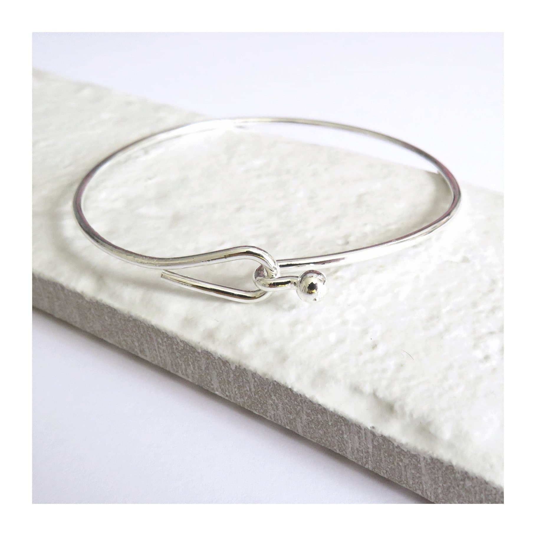 Silver hoop bangle with a plain, rounded silver finish.