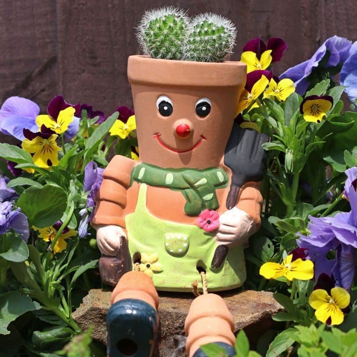 Terracotta pot man planter with a small flower planted in the top