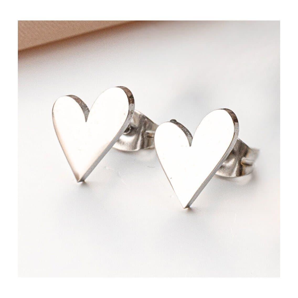 Tilted heart stud earrings in stainless steel with butterfly backs