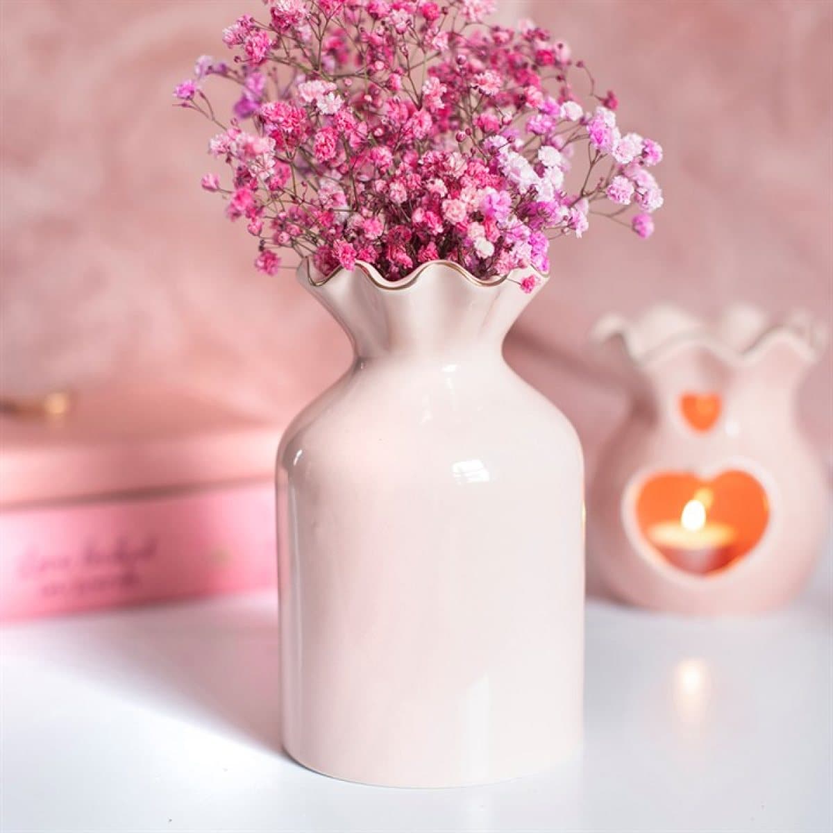 Pink fluted ceramic flower vase with a ridged body on a plain background