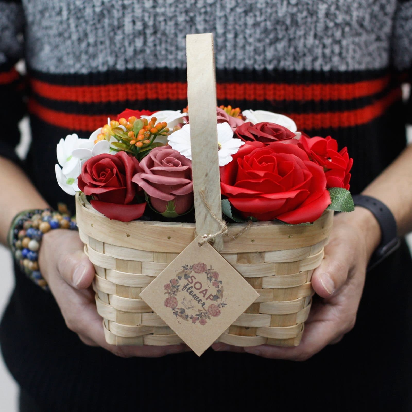 Pink soap roses, hyacinths and a sunflower arranged in a small wicker basket