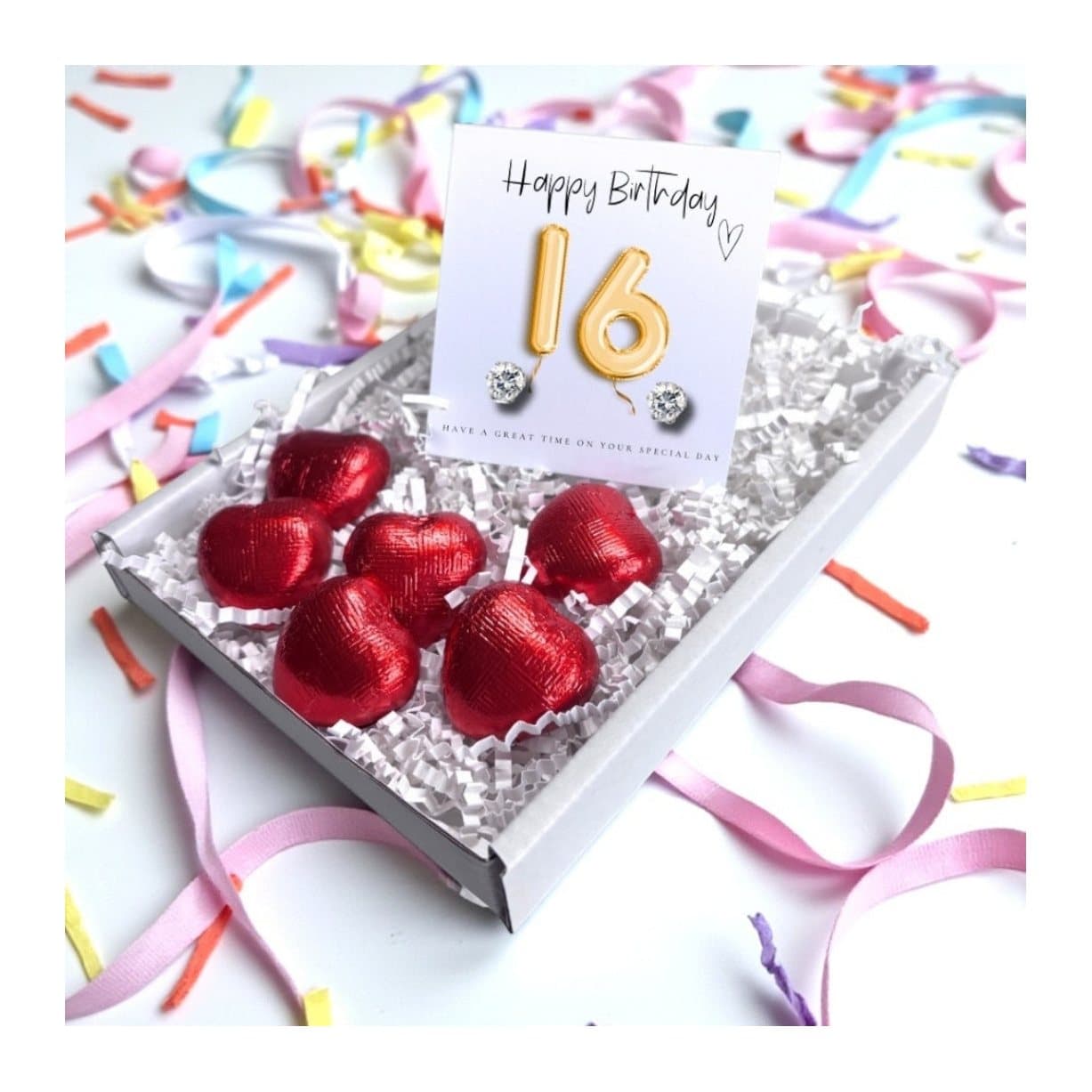 Cubic zirconia earrings and red foiled chocolate hearts on a gold balloons card