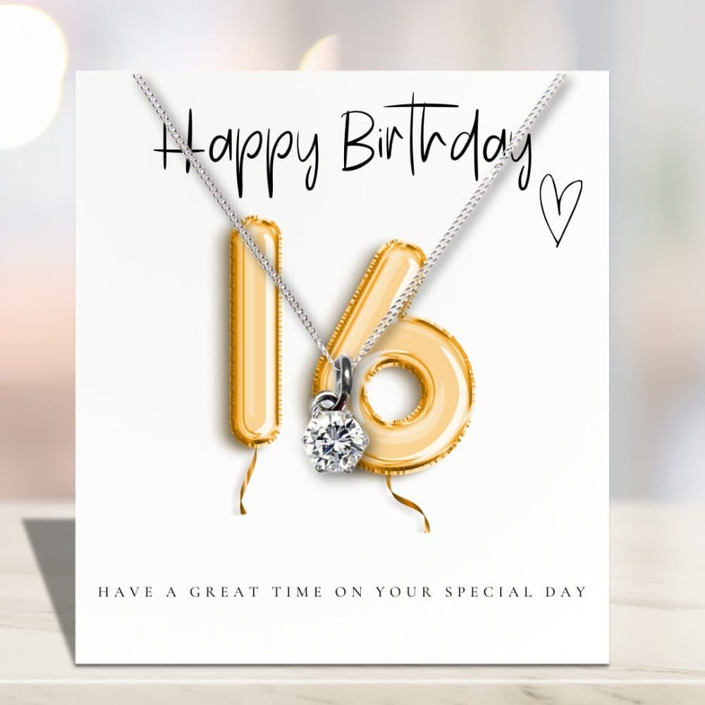 Silver necklace with a cubic zirconia charm beside a gold balloons message card