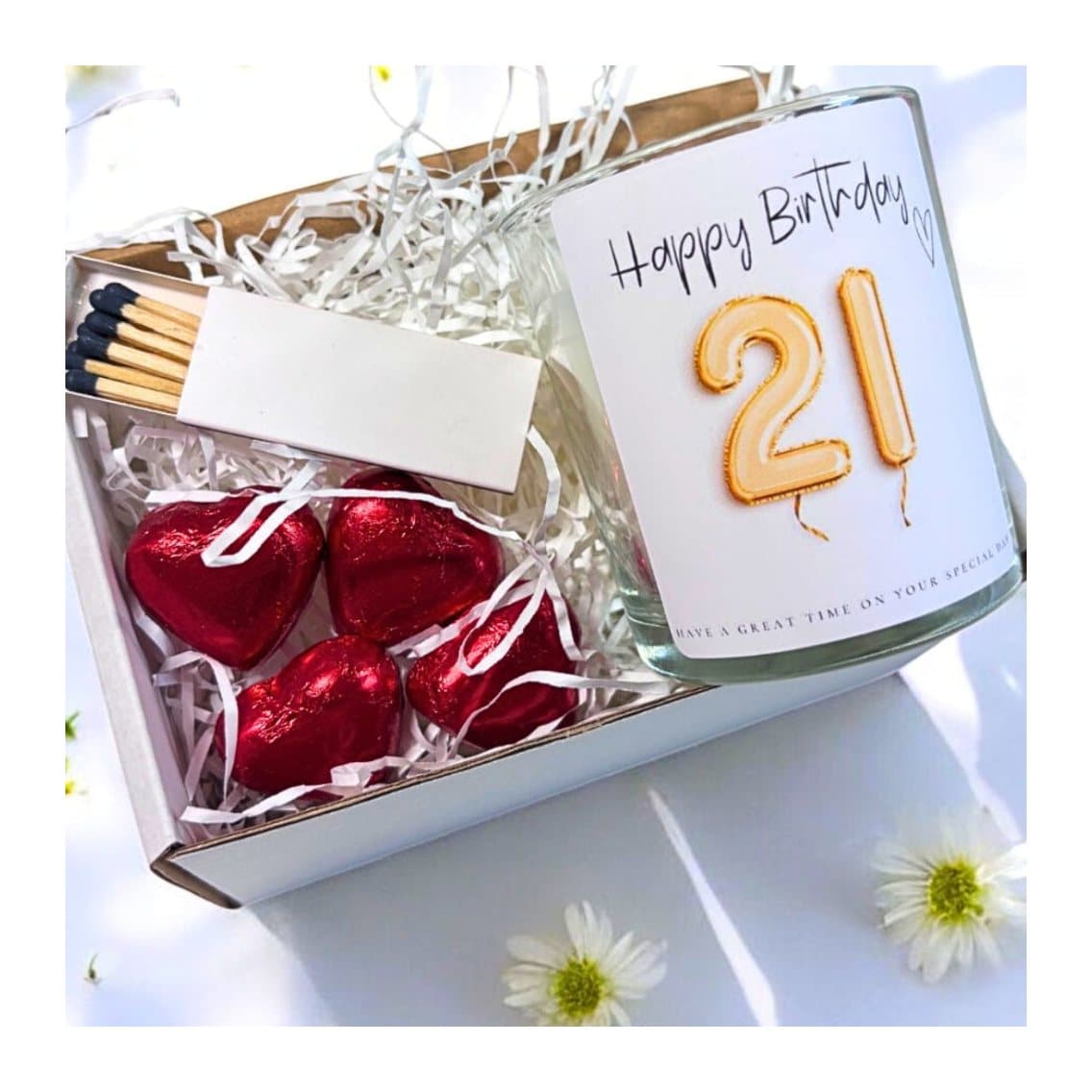 Gold balloon 21st birthday candle beside milk chocolate hearts and matches