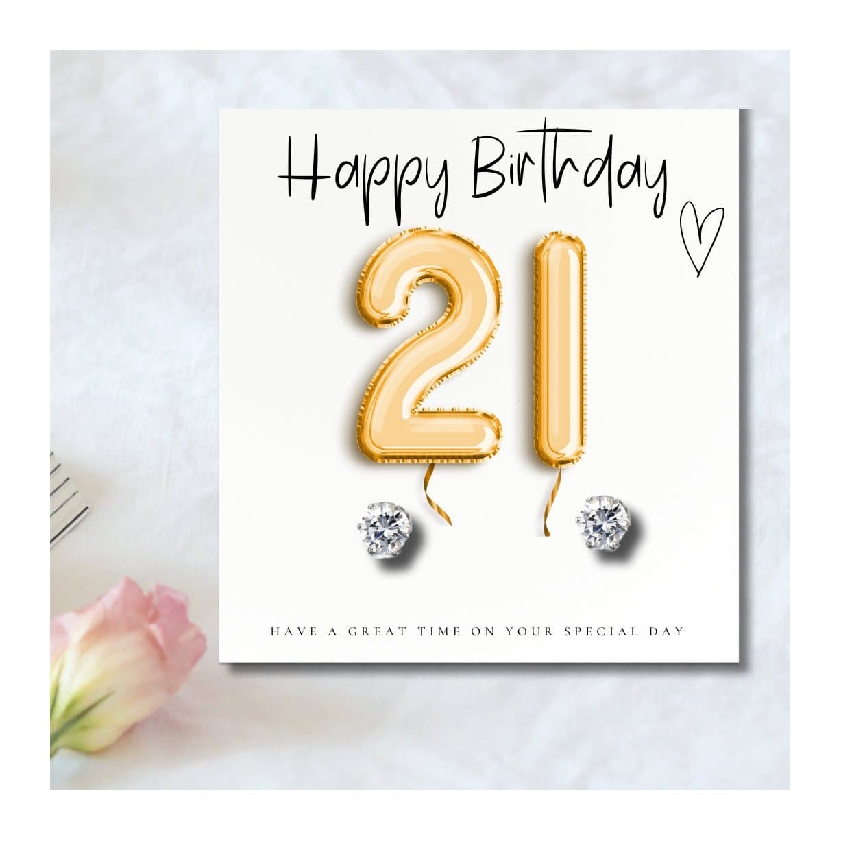 Silver cubic zirconia stud earrings beside a gold balloons 21st birthday message card