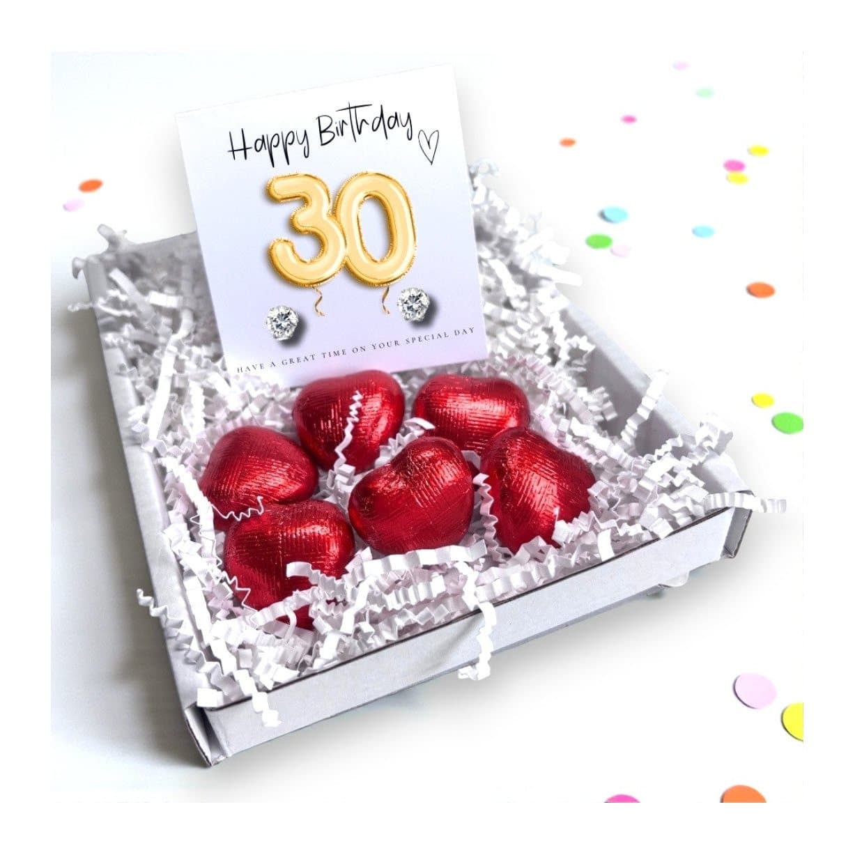 Cubic zirconia stud earrings and red foiled chocolate hearts on a gold balloons card