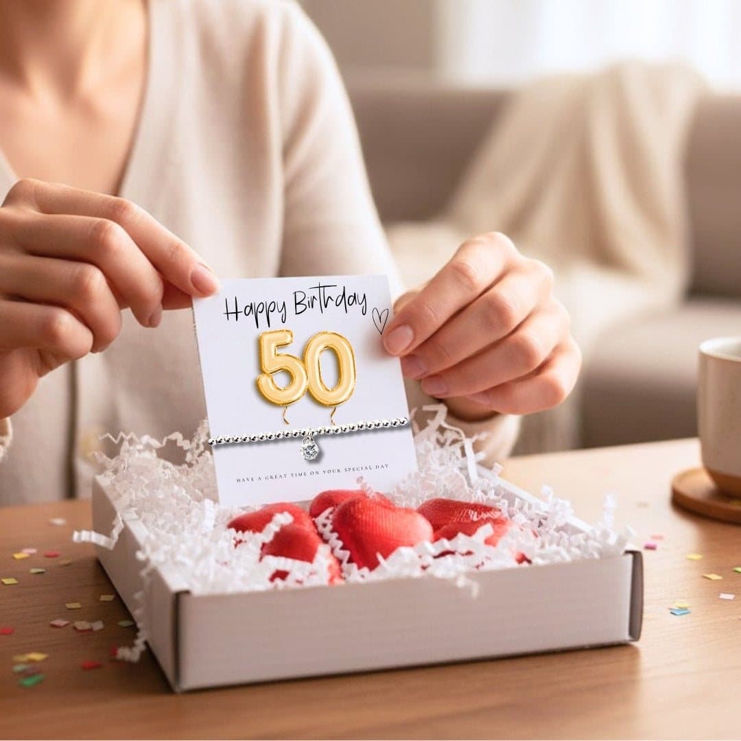 50th birthday gift box with a beaded bracelet, gold balloon card and chocolate hearts