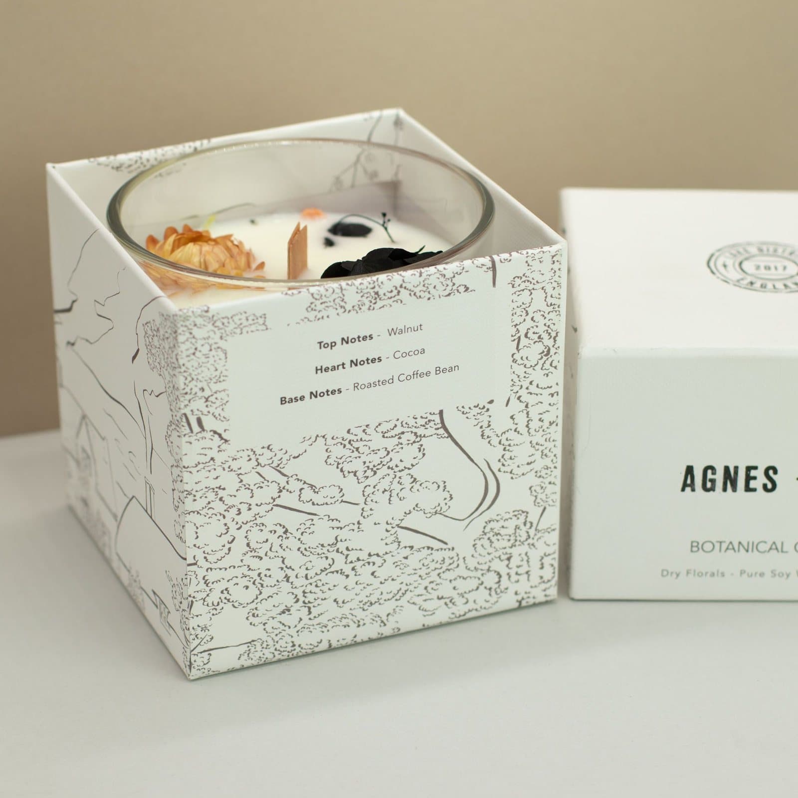 Soy wax candle in a clear glass jar with dried florals in the wax