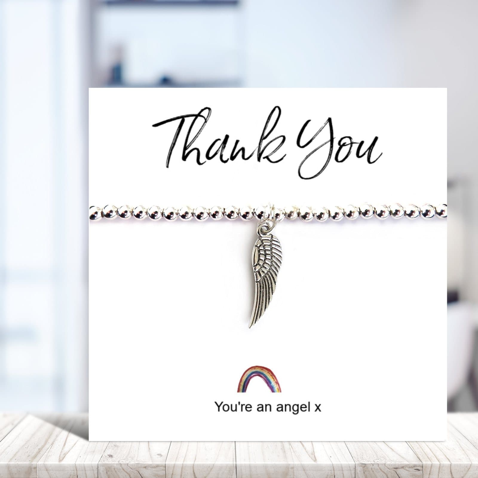 Silver beaded bracelet with an angel wing charm on a rainbow thank you card