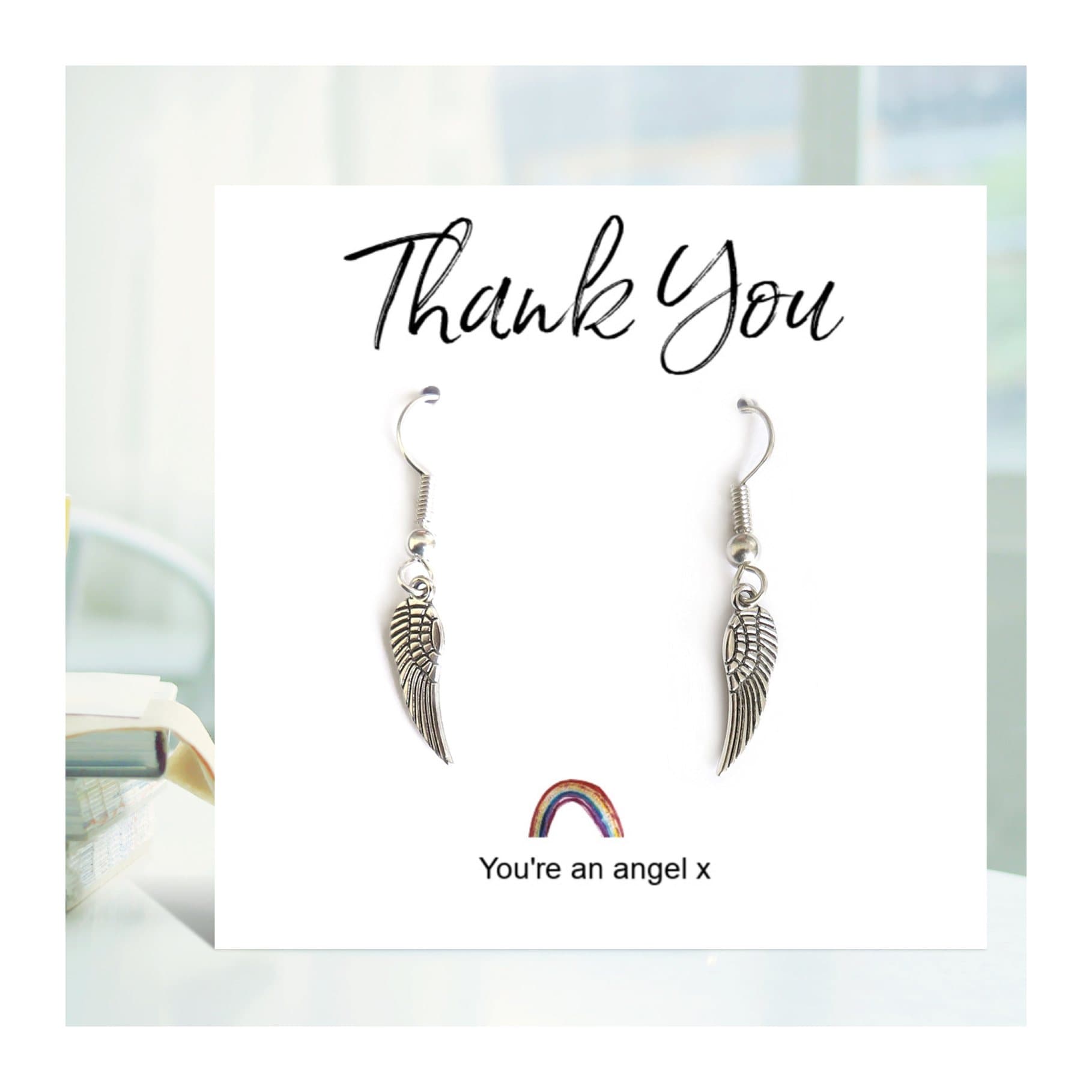Angel wing drop earrings on a rainbow thank you card