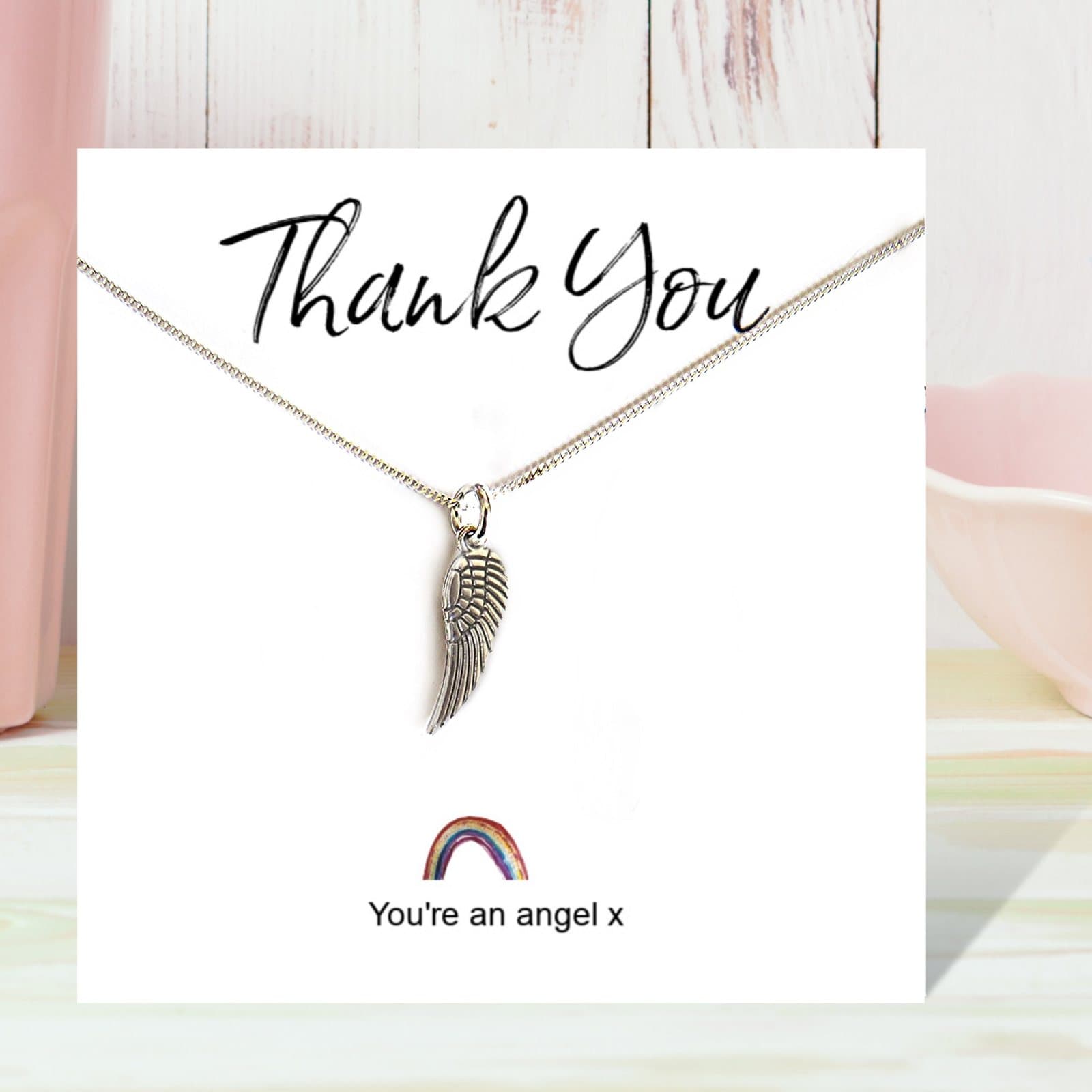 Silver angel wing necklace on a rainbow thank you card