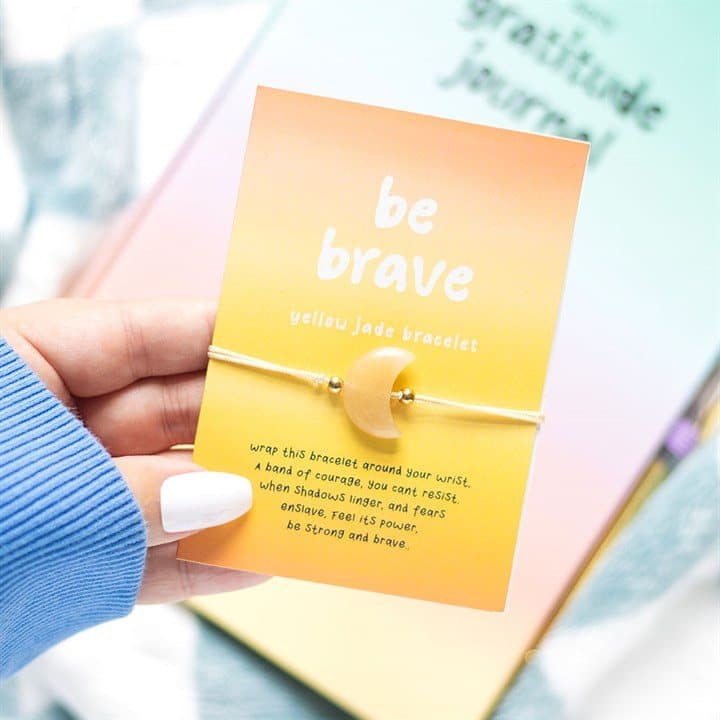 Yellow jade crystal moon bracelet on a cardboard card reading Be brave