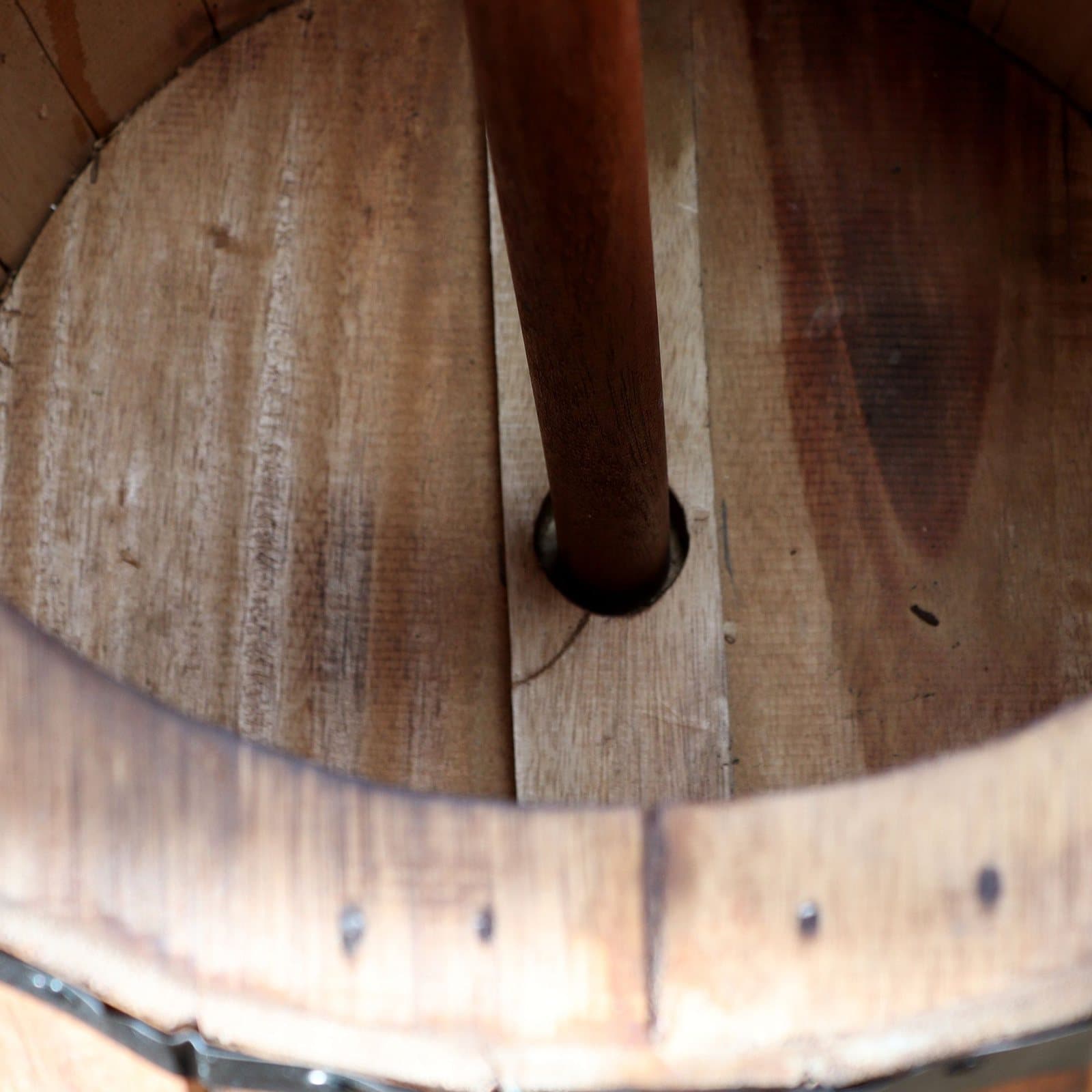 Natural wood barrel stool with dark metal-style bands and a central hole