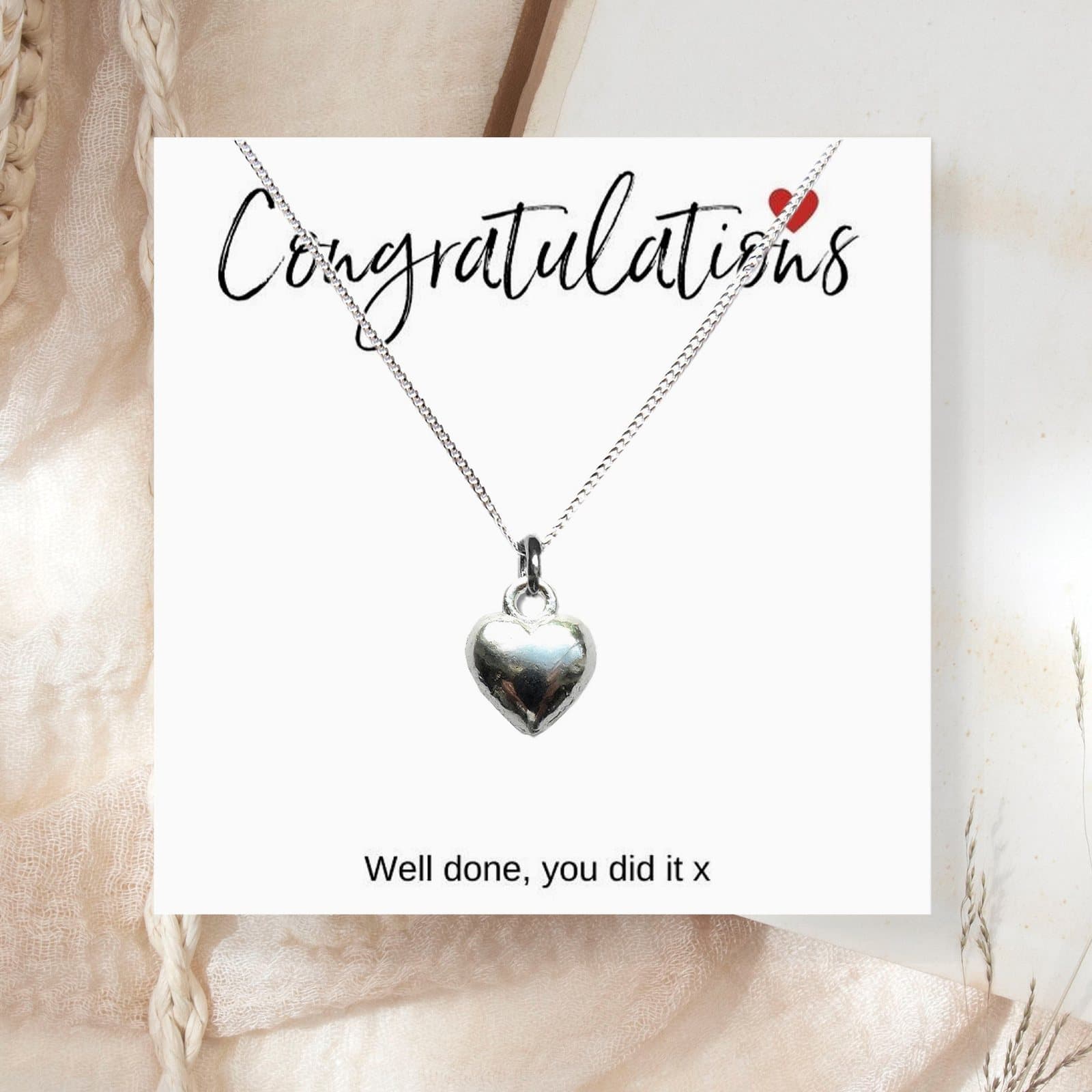 Silver heart charm necklace presented on a congratulations message card