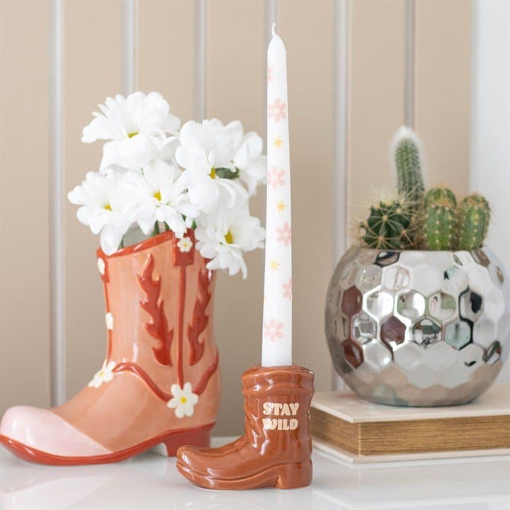 Brown cowboy boot holding a white floral taper candle