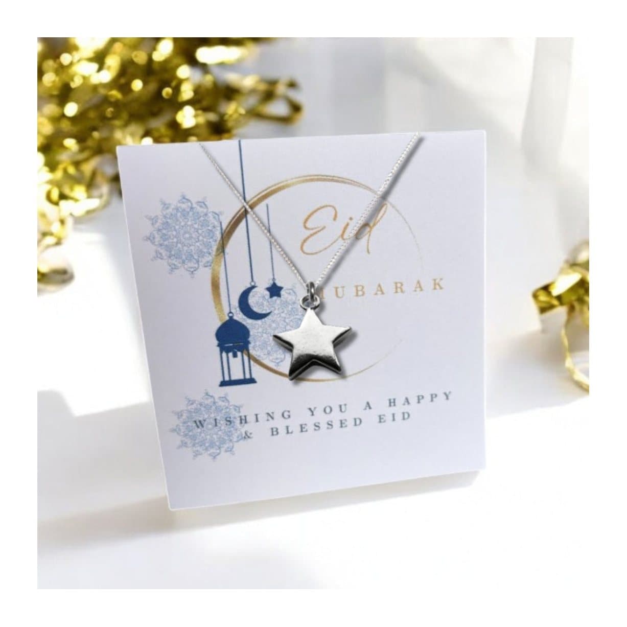 Silver star necklace on an Eid Mubarak message card with a moon design