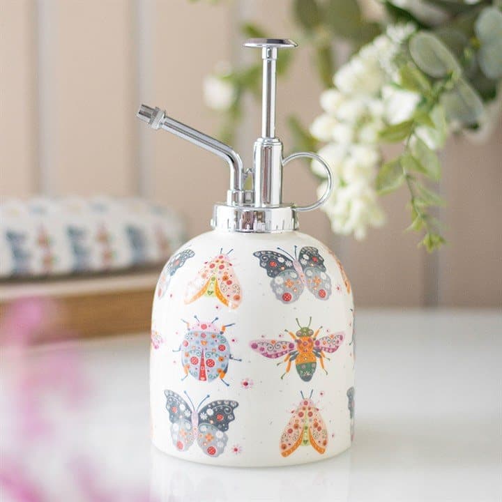 Ceramic plant mister with a pastel floral bug design and silver nozzle