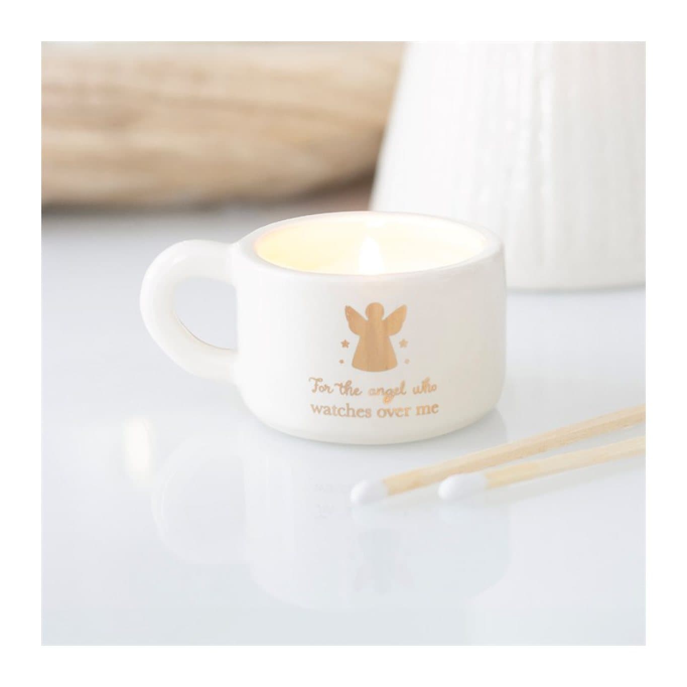 Off-white ceramic tealight holder with a metallic gold angel and handle