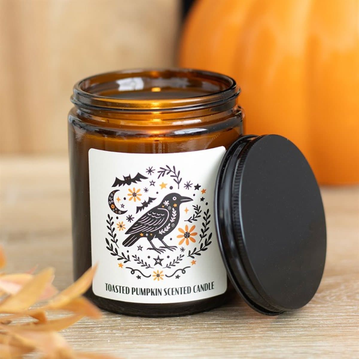 Brown apothecary-style glass candle jar with a folk raven design