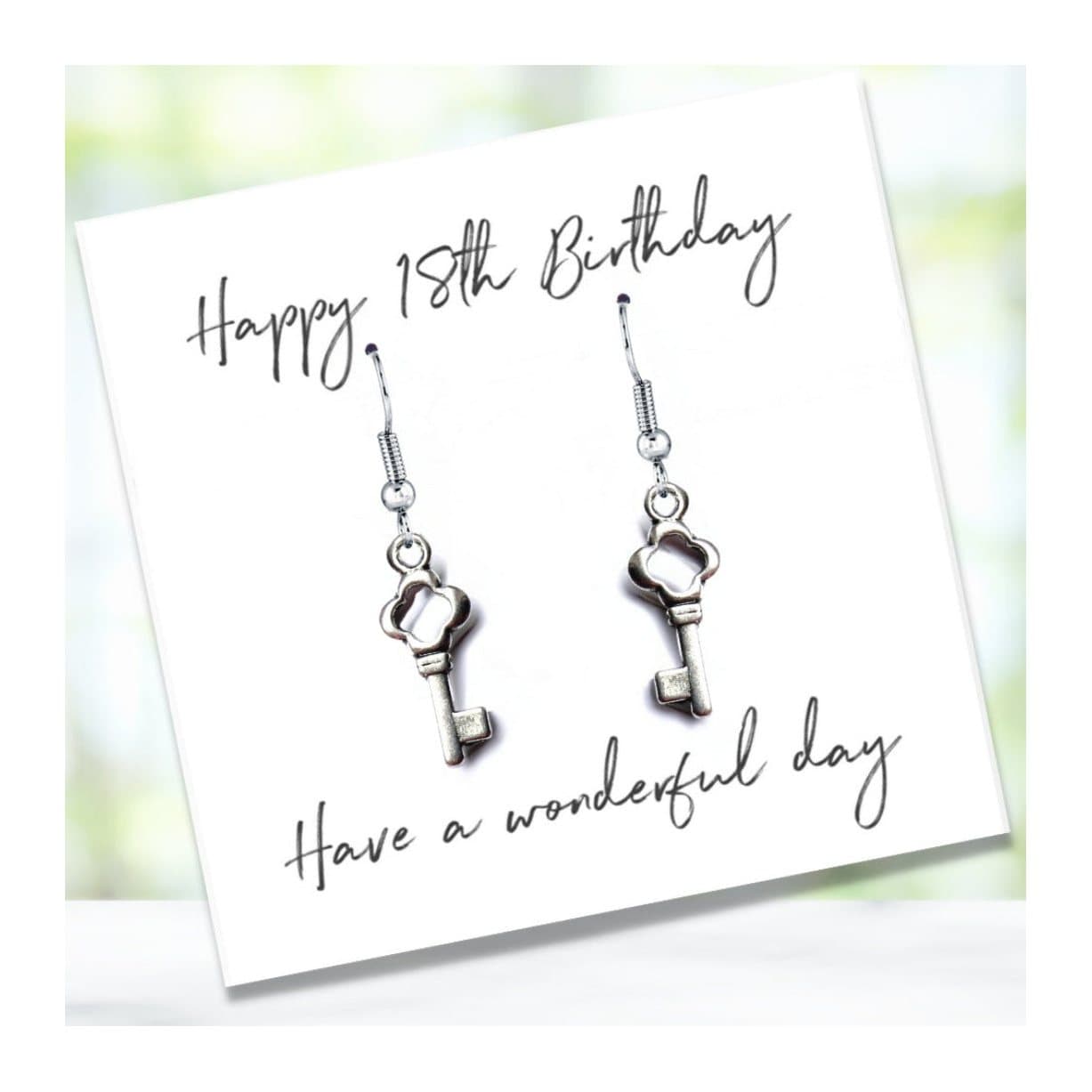 Drop earrings with a key charm beside a Happy 18th Birthday message card