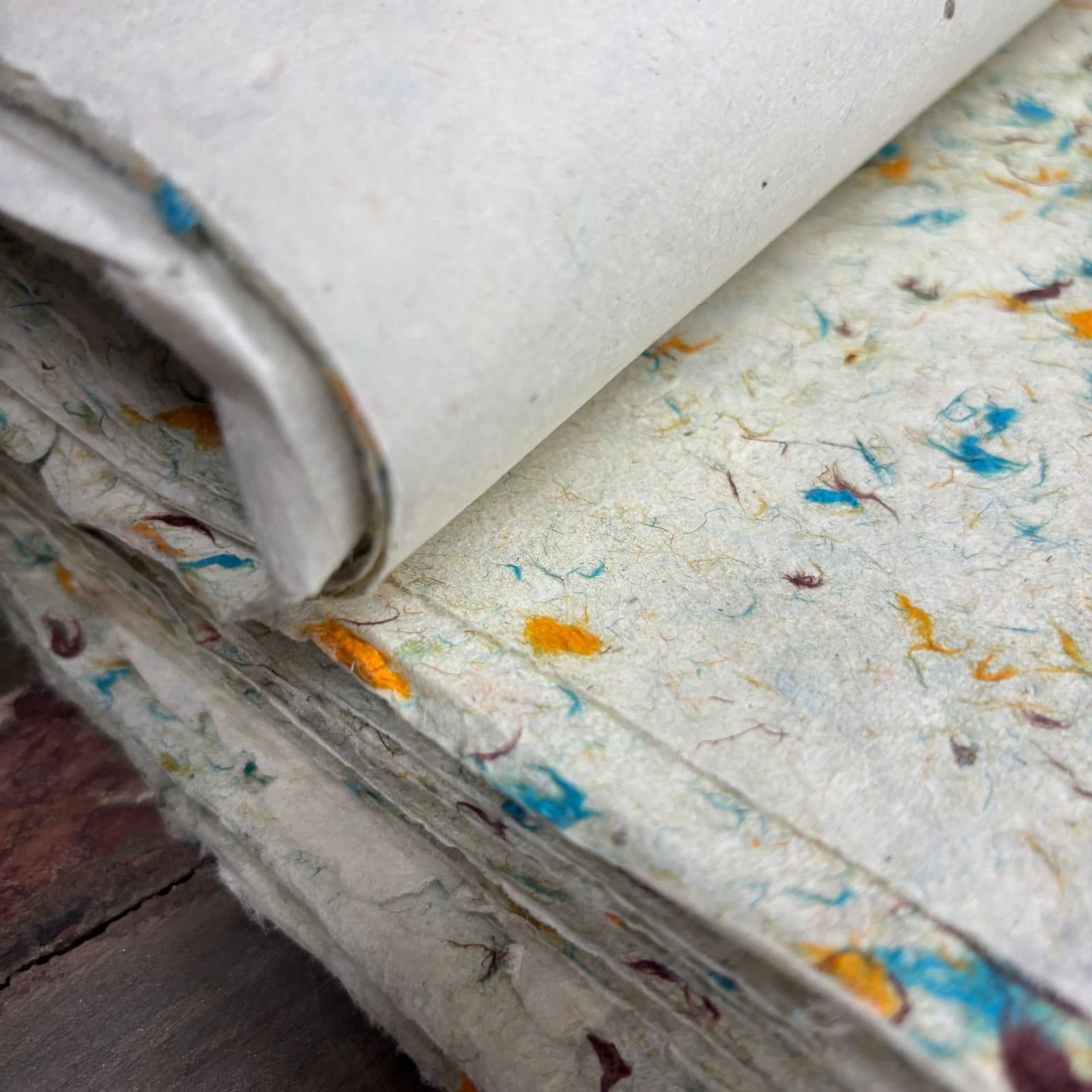 Handmade Lokta paper with visible grass fibres on a soft creamy base