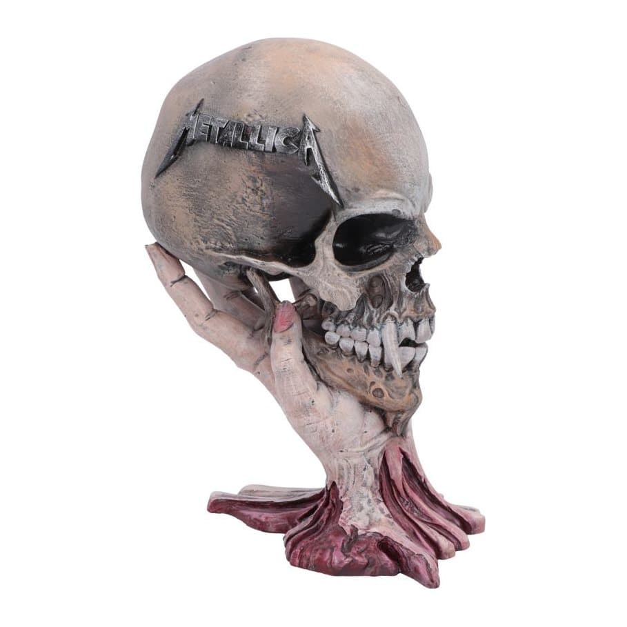 Metallica fanged skull figurine held up by a human hand